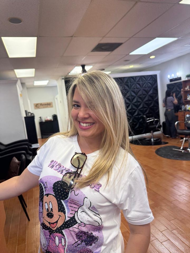 Smiling client with sun-kissed blonde layers in the salon